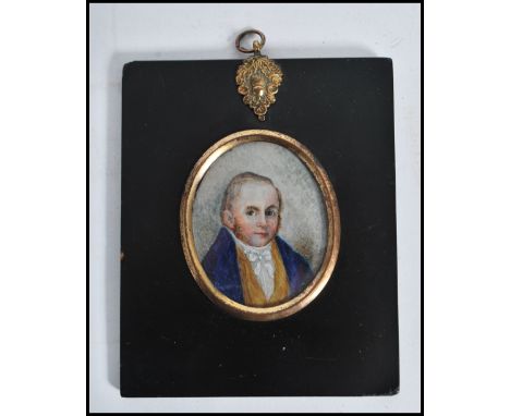 A 19th century watercolour on ivory miniature painting of a young man, set within an ebonised frame with inset oval gilt surr