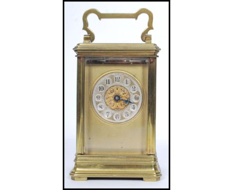 An early 20th century brass carriage clock hacing gilded face with enamel button numerals with faceted hands. Handle top over
