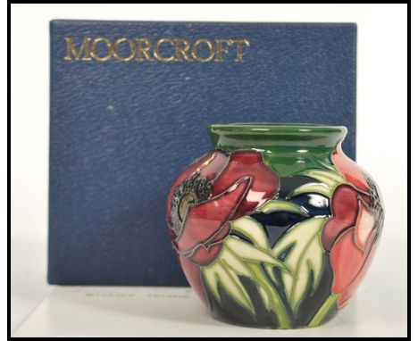 A Moorcroft ceramic vase tube lined decorated with flowers in the Anemone Tributte pattern complete in original box C2002 sci