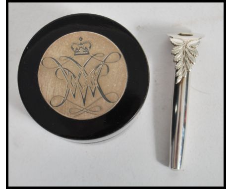 A silver hallmarked button hole together with an ebonised lacquered pill pot / snuff pot having a silver hallmarked roundel t