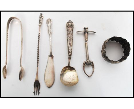 A group of silver hallmarked flatware to include a pickle fork with twist stem and apostle finial, a pair of sugar nips beari