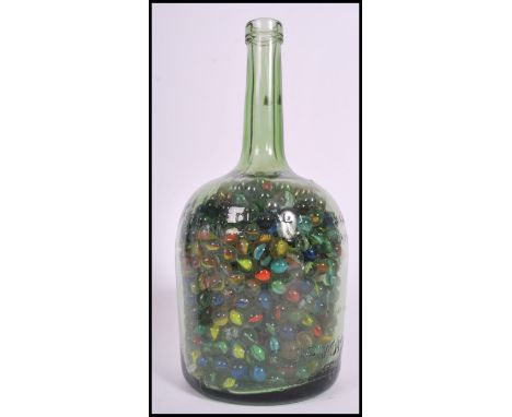A large collection of vintage 20th century glass marbles contained within a large glass bottle containing various designs and