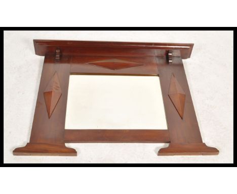 A Victorian mahogany overmantel wall mirror in the Arts &amp; Crafts manner. The central bevelled mirror with shaped panel si