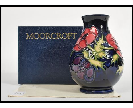 A Moorcroft ceramic vase tube lined decorated with flowers in the Anemone Blue pattern complete in original box diamond marks