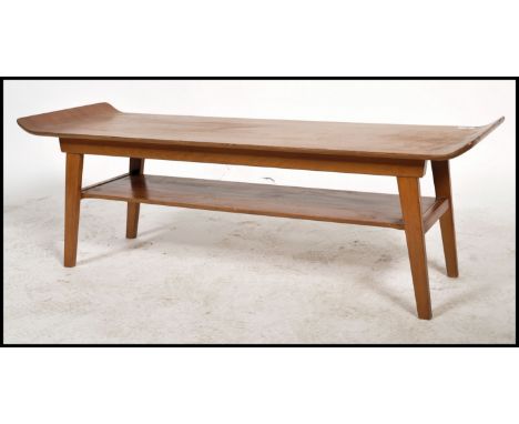 A Vintage retro teak wood mid century coffee table raised on shaped legs with under mag shelf, the top with raised flip up ed