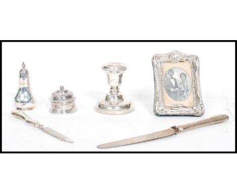 A collection of silver hallmarked items to include a pepper cruet, candle stick, easel picture frame, lidded pot etc please r