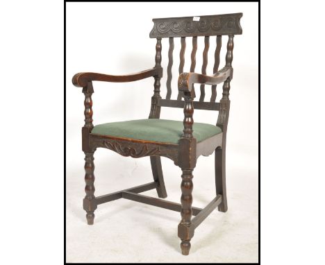 An early 20th century oak carver armchair being raised on bobbin turned supports with stretchers. Above a wavy back rest with