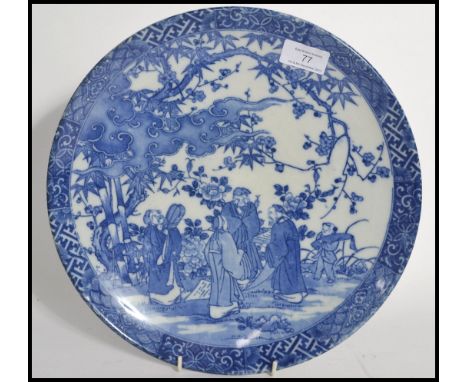 A 19th century blue and white Chinese ceramic charge plate depicting domestic scenes of elders with blue character marks to b