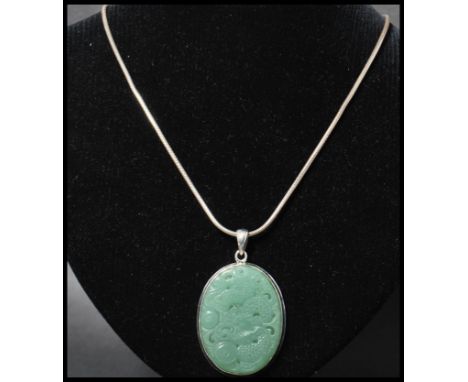 A 925 silver pendant necklace strung with a carved jade pendant with dragon decoration strung on a snake link&nbsp; chain. Me