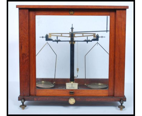 A pair of early 20th century mahogany cased scientific scales. The glass case with inset scales on adjustable base