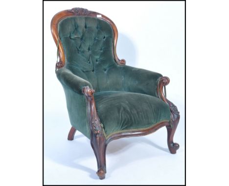 A Victorian mahogany spoon back library chair, with button back green velour upholstery, pad seat and arms on shaped legs and