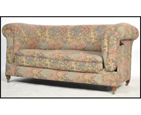 A Victorian mahogany tapestry upholstered drop arm Chesterfield sofa settee being raised on turned legs with barrel arms and 