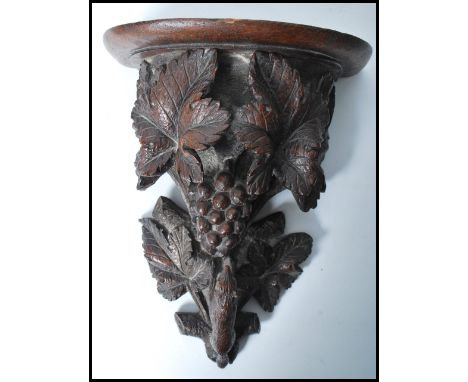 A 19th century Black Forest carved pine wall bracket, with shaped and moulded shelf, supported by a carved depiction of the f