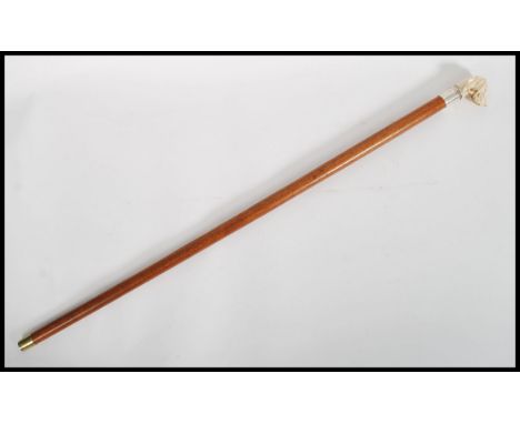 A vintage 20th century walking stick cane. The tapering wooden shaft having a silver&nbsp;stamped collar with carved ivorine 