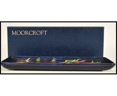 A Moorcroft ceramic pin tray of rectangular form tube lined decorated with flowers in the Anemone Blue pattern complete in or