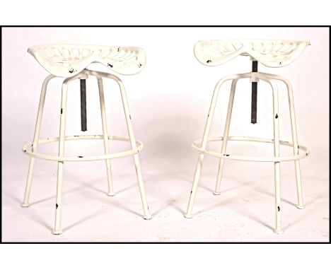 A pair of contemporary retro Industrial stools with tractor seat tops on swivel columns and tubular metal frames below. Measu