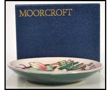 A Moorcroft ceramic pin tray coaster plate of circular form tube lined decorated with flowers in the Blakeney pattern complet