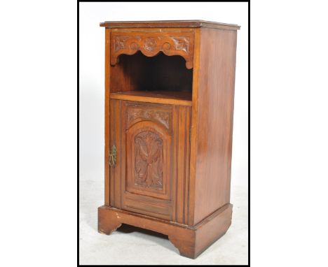 An Edwardian mahogany pedestal pot cupboard raised on a bracket plinth base with carved door cupboard having open shelf above