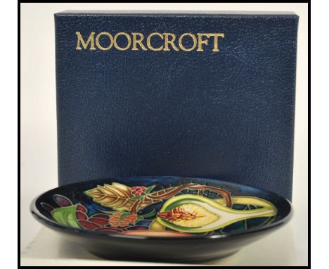 A Moorcroft ceramic pin tray coaster plate of circular form tube lined decorated with flowers in the Queens Choice pattern co