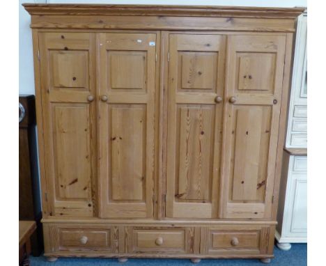 A modern stripped pine wardrobe with four fielded panel doors on a three-drawer base, 193cm wide, 196cm high