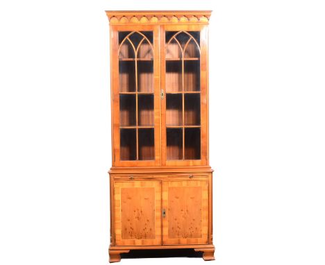 A reproduction yew wood bookcase, of small proportions, arched glazing bars to the upper section enclosing adjustable shelves