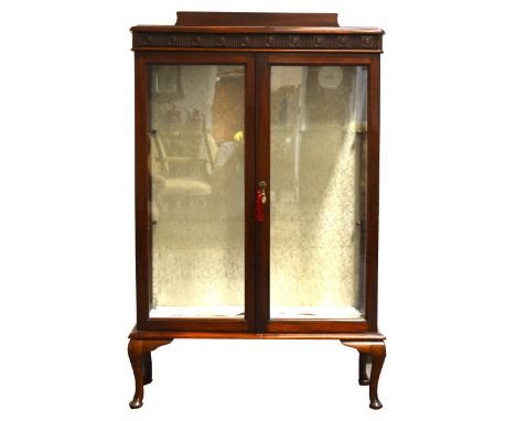 A stained mahogany display cabinet, carved frieze above pair of glazed doors, enclosing two glass shelves, fitted with light 