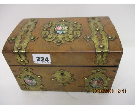 A late Victorian walnut tea caddy with studded brass strapwork and three porcelain floral plaques, the hinged lid enclosing t