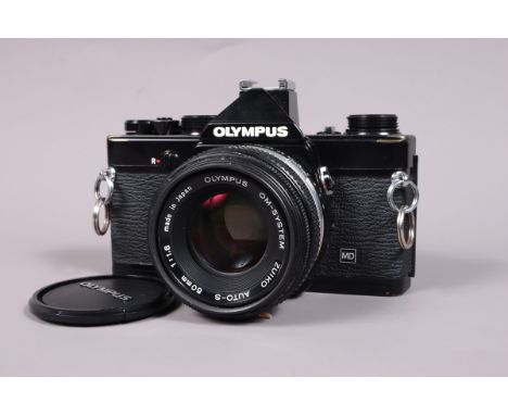 An Olympus 0M 1n SLR Camera, black, serial no 1988246, shutter working, meter responsive, self timer working, body G, some br