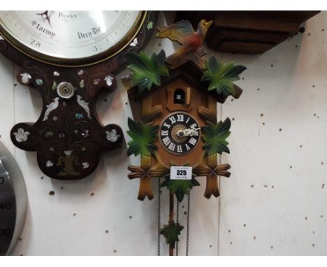 A wall mounted Cuckoo Clock, the case carved with oak leaves, matching oak leak pendulum with two pine cone weights.