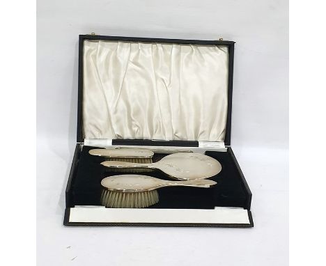 Four-piece silver-backed dressing table set comprising hand mirror, two brushes and a comb, with engine-turned and floral dec