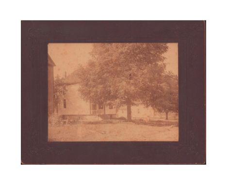 Antique black and white photo depicting a Victorian farmhouse with a large tree, possibly maple, in the front yard. Silver ge
