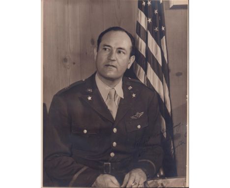 Large candid portrait of General Kenneth P. McNaughton seated in a wood paneled room next to American Flag. Silver gelatin pr