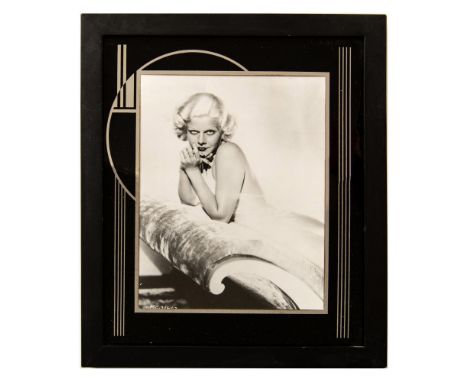 High quality photographic print depicting American actress Jean Harlow leaning on a velvety chaise lounge with a seductive ex