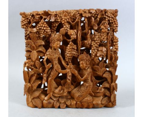 AN INDIAN CARVED RELIEF PANEL OF TWO FIGURES, the figures carved in relief around native foliage, the back inscribed ( see ph