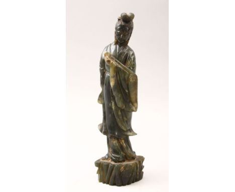A 20TH CENTURY CHINESE CARVED JADE FIGURE OF GUANYIN, stood upon a stylized stump base holding a Ruyi-scepter, 24cm high.