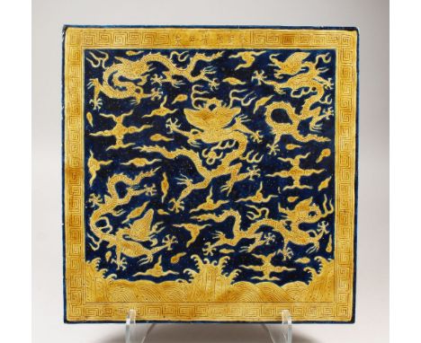 AN UNUSUAL LARGE CHINESE MING STYLE YELLOW &amp; BLUE PORCELAIN TILE, with incised decoration of dragons above stylized waves