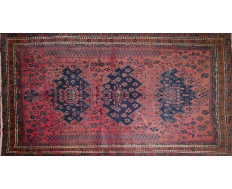 A North West Persian Kurdish carpet, triple eagle motifs on a pale rouge field, within stylised geometric border, 286 x 182cm