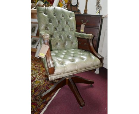 A mahogany swivel desk chair, with button back leather upholstery, raised on castors 