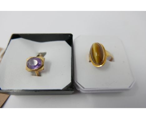 Two 9 ct yellow gold rings, one set with an oval-shaped tiger's eye cabochon Size L, 3g the other set with a faceted amethyst
