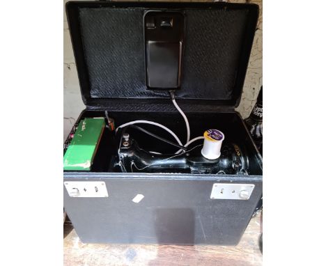 A circa 1950s - 1960s Singer Featherweight portable electric sewing machine, model 221K, with accessories, pedal and instruct