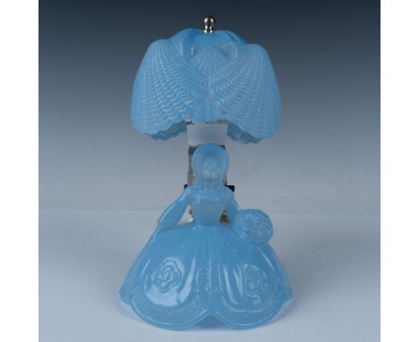 A sky blue lamp shaped like a country belle in her dress, holding a bouquet of flowers, topped with a lamp shade that resembl