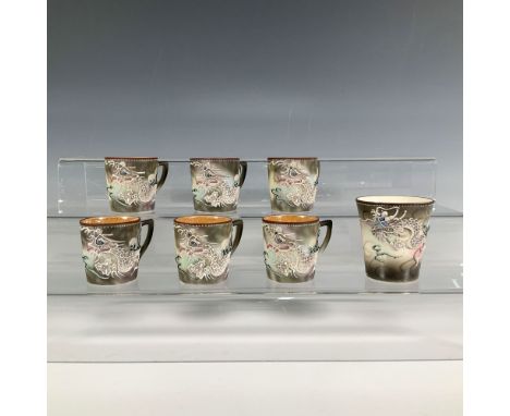 A set of 6 brown and green mugs, each decorated with low relief art of a dragon soaring through the sky, accompanied by a mat