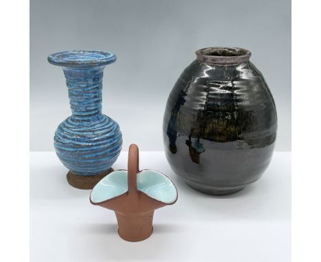 Features one rustic blue vase with deep relief carved edges and a thin band of unglazed raw clay at the base, one glossy blac