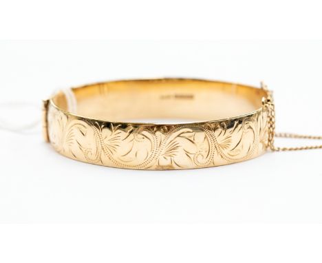 A 9ct gold hinged bangle, foliate engraved decoration, total gross weight approx 38.5 grams (boxed)