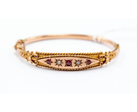 A Victorian 9ct gold bangle set with diamonds and red paste stones, rope border, total gross weight approx. 8.9gms.