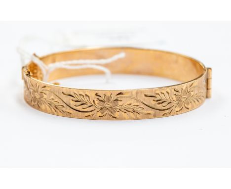 An unmarked 9ct gold bangle, hinged, floral engraved to top, weight approx. 18.6gms.