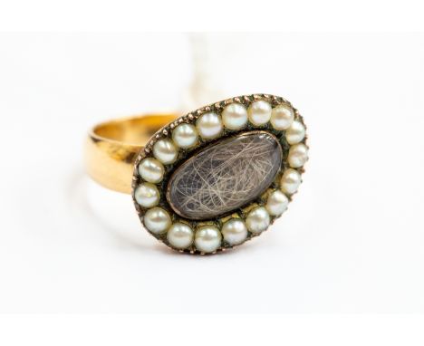 A 19th Century mourning ring, enclosing hair within pearl border, mounted on a later polished shank tested as 18ct gold, size