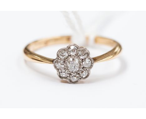 An 18ct gold and diamond daisy ring, centre diamond with eight surrounding, size M, approx 2.2gms
