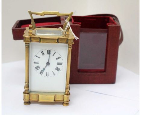 A brass carriage clock with white enamel dial, Roman numerals, bevelled glass and three quarter turned pilasters at each corn