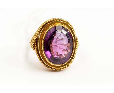 A large amethyst dress ring, oval stone approx 12mm x 16mm, rope edge, unmarked 18ct gold, size O½, total gross weight 10gms.